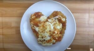 Heart-shaped chicken parmigiana on a white plate.